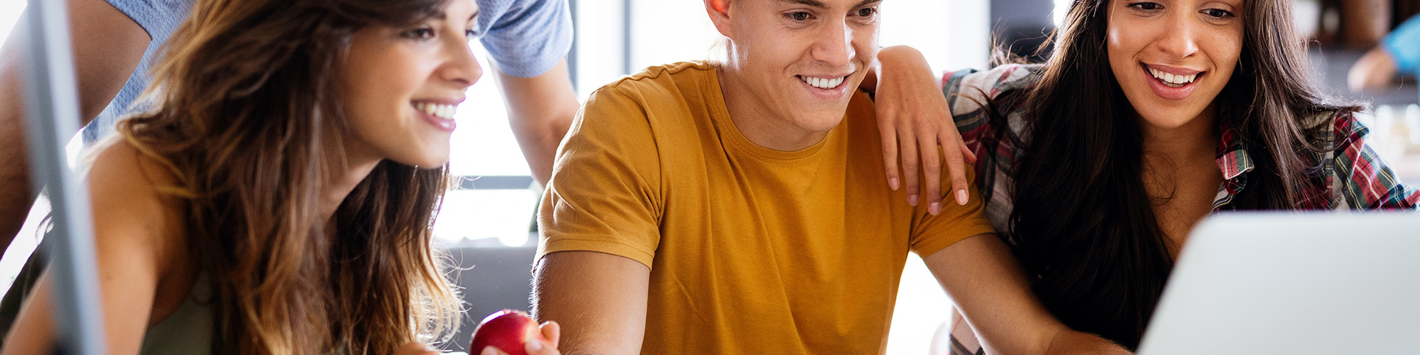 Vier junge Erwachsene schauen zur Weiterbildung auf einen Laptop